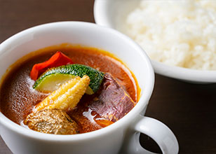 【スープカレー】 札幌発祥グルメ。複数のスパイスや出汁が入ったスープ状のカレーに大きめに切った野菜やお肉が入った料理です。 ライスをスープに浸して食べる、ライスにスープをかけて食べる、スープ・ライスを別々に食べる等、ご自由にお召し上がりください。